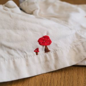 Deux champignons rouges brodés sur un short blanc