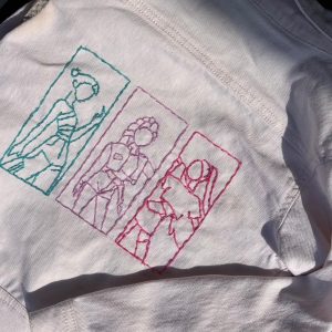 veste en jeans blanche bordée avec les silhouettes rose, bleu et violet des chanteuses de Kpop Demon Hunters
