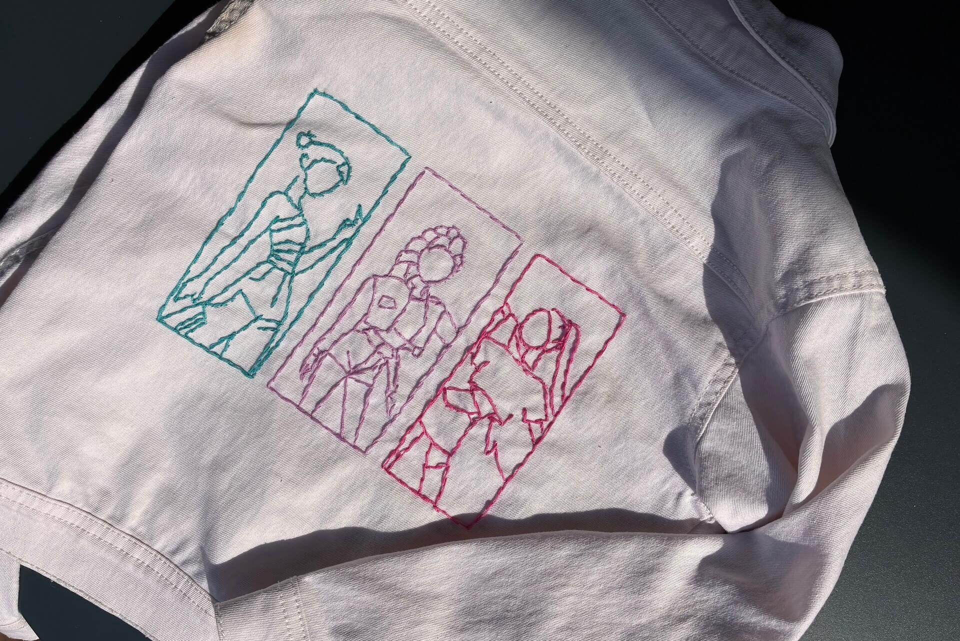 veste en jeans blanche bordée avec les silhouettes rose, bleu et violet des chanteuses de Kpop Demon Hunters