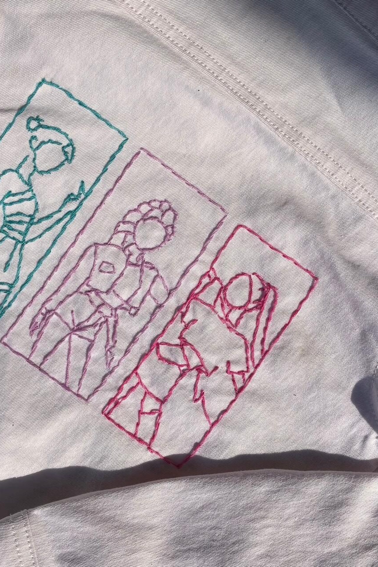 veste en jeans blanche bordée avec les silhouettes rose, bleu et violet des chanteuses de Kpop Demon Hunters